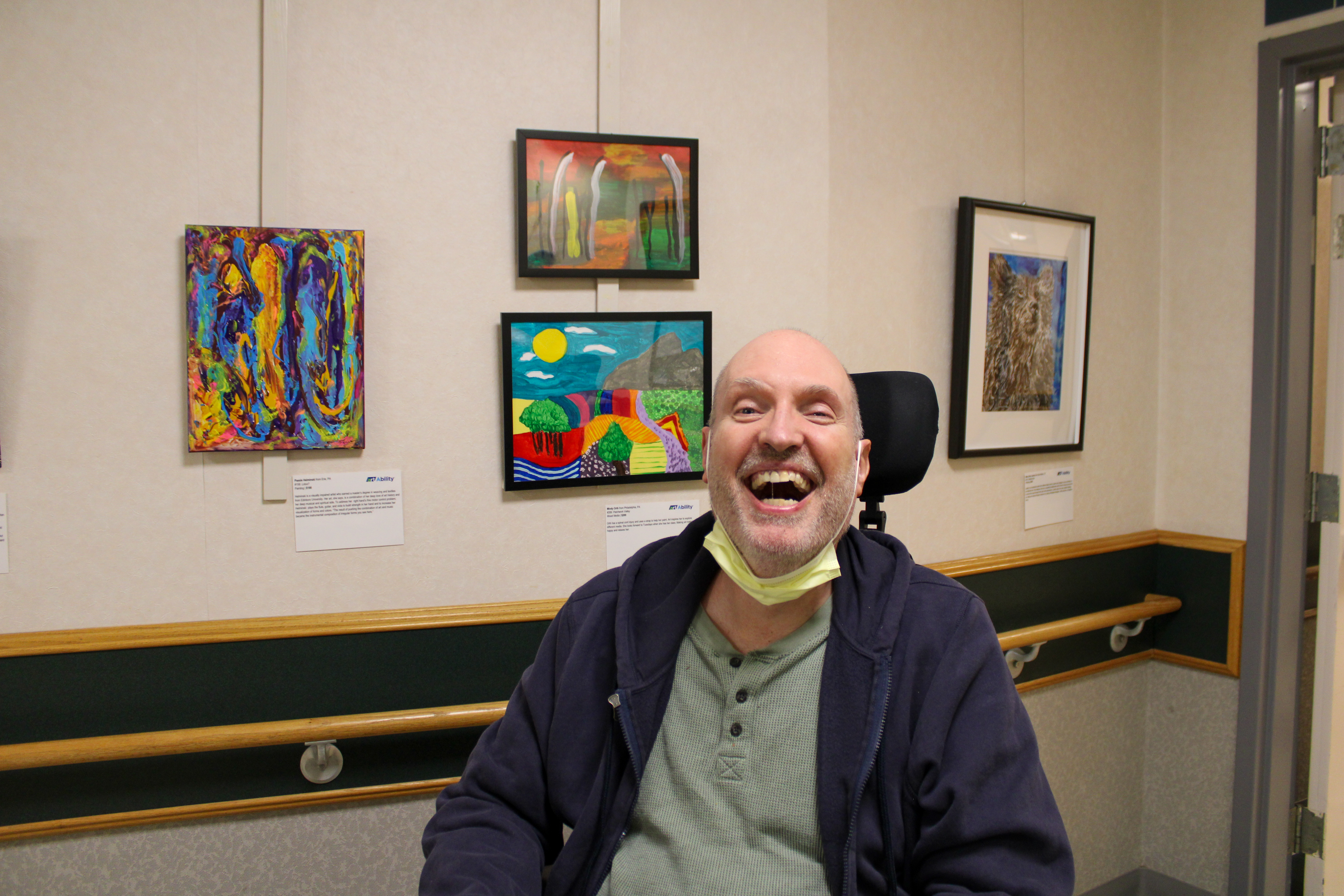 Inglis House Resident smiles in front of his artwork
